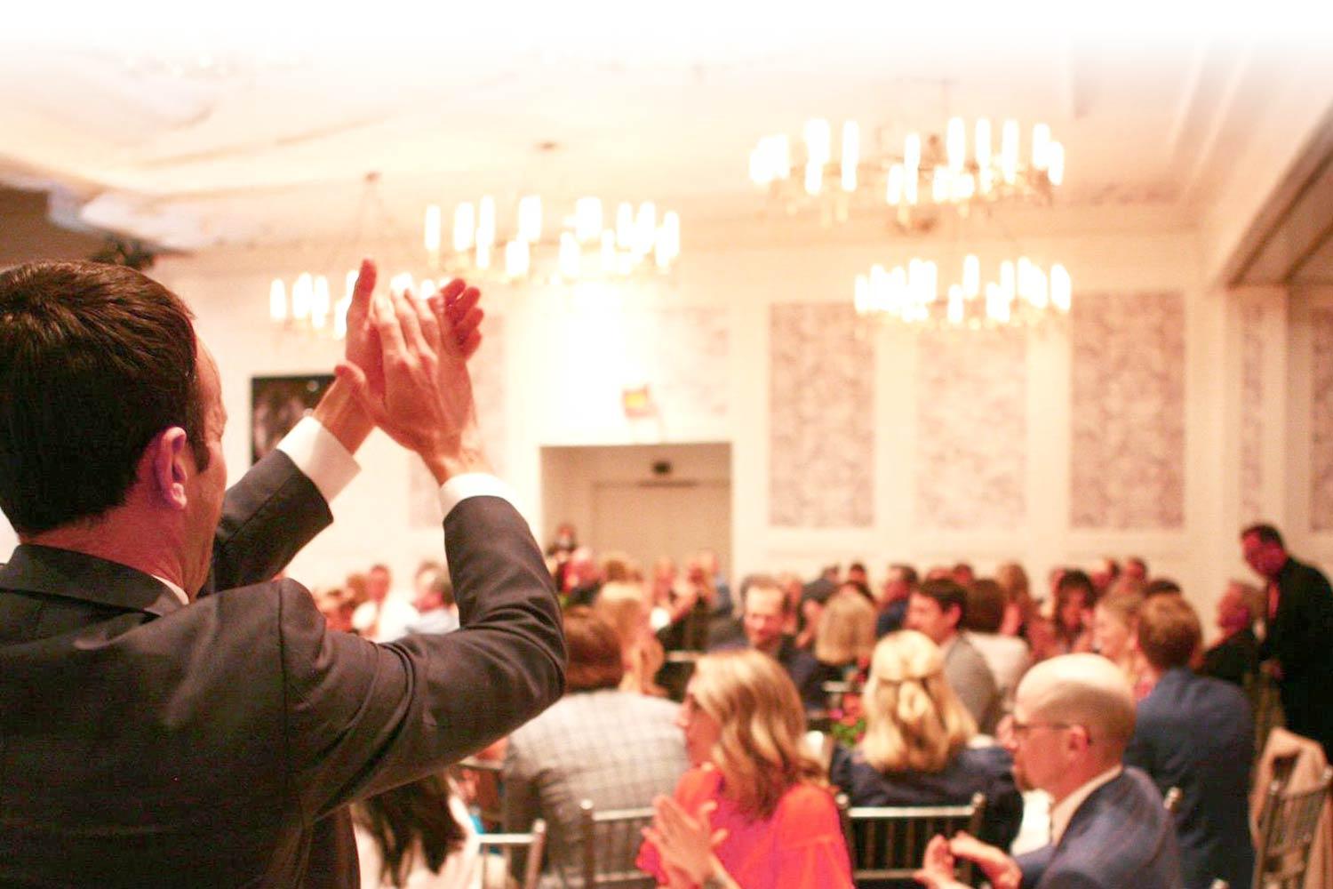 NKF Gala room with chandeliers and people clapping